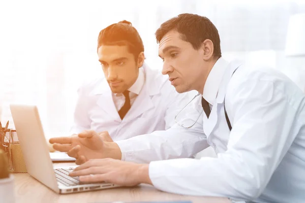 Két orvos keres valamit a laptop az orvosi rendelő. — Stock Fotó