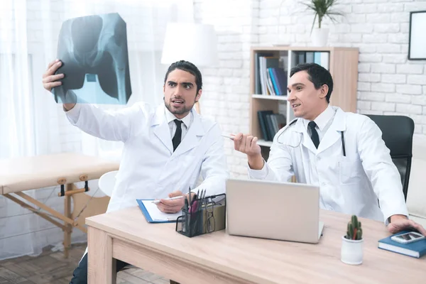 Dos doctores miran la radiografía en el consultorio médico . —  Fotos de Stock
