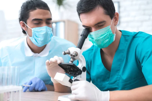 El médico examina la muestra de sangre del paciente en un microscopio . —  Fotos de Stock