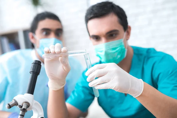 El médico vierte líquido de un tubo de ensayo a otro . —  Fotos de Stock