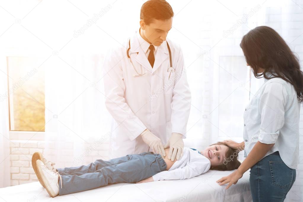 The doctor in white gloves massages the belly of a sick boy.