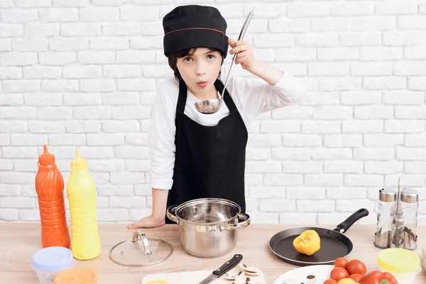 The little boy is mastering the profession of cook. The dark-haired boy wants to become a cook. He plays in the cook and prepares dinner.