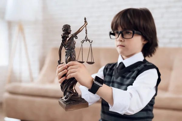 スーツとネクタイの少年は Femida の置物を持っています 黒髪の少年がメガネは正義の像に見えます 少し将来弁護士 — ストック写真