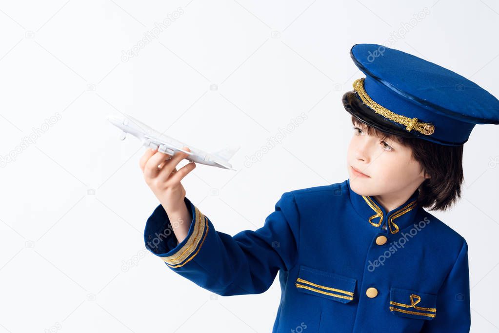 The little boy learns the profession of a pilot. The dark-haired boy wants to become a pilot. He plays with a toy airplane in the pilots uniform.