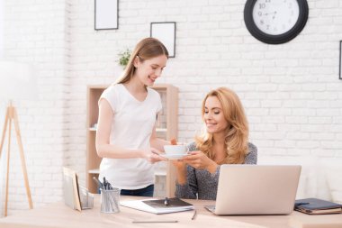 Kızı Anne çay bir fincan getirdim. Bir kadın bilgisayarda çalışıyor. O kız ona yardımcı olur çok memnun oldu. O gülümsüyor.