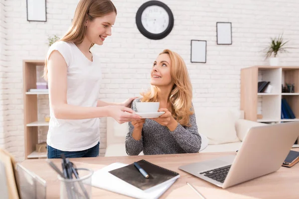 Kızı Anne çay bir fincan getirdim. Bir kadın bilgisayarda çalışıyor. O kız ona yardımcı olur çok memnun oldu. O gülümsüyor.