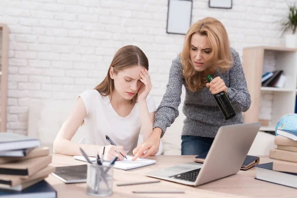 Kızı okul ödevi düzgün yapamaz. Kadın bu yüzden kızgın. O kızı çığlıklar ve bir şişe alkol elinde tutan.