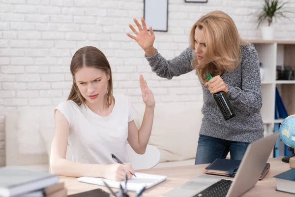 Kızı okul ödevi düzgün yapamaz. Kadın bu yüzden kızgın. O kızı çığlıklar ve bir şişe alkol elinde tutan.