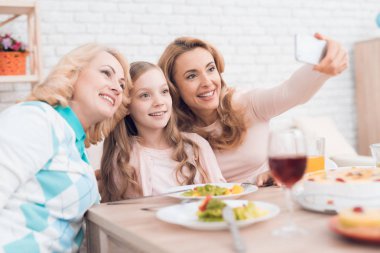 Anne, Büyükanne ve torunu selfie yemek yapmak. Evde yemek var. Onların masaya sebze ve tatlılar ellerinde.