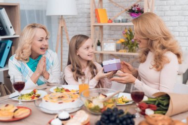 Kız anne ve Büyükanne için bir hediye 8 Mart olur. Onlar şenlikli masaya oturuyorlar.