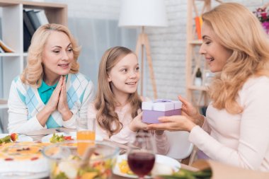 Kız anne ve Büyükanne için bir hediye 8 Mart olur. Onlar şenlikli masaya oturuyorlar.