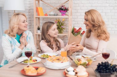 Kız çiçek annesine tatil için verir. Onlar üzerinde orada sebze ve tatlılar bir şenlikli masaya oturmak.