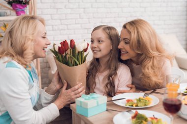 Kız çiçek büyükannesi için tatil için verir. Onlar üzerinde orada sebze ve tatlılar bir şenlikli masaya oturmak.