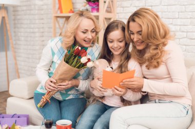 İki yetişkin kadın ve bir kız bir tebrik kartı arıyoruz. Bu annem ve büyükannem kızın. Onlar evde akşam yemeği.