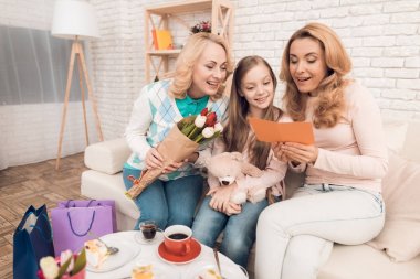 İki yetişkin kadın ve bir kız bir tebrik kartı arıyoruz. Bu annem ve büyükannem kızın. Onlar evde akşam yemeği.