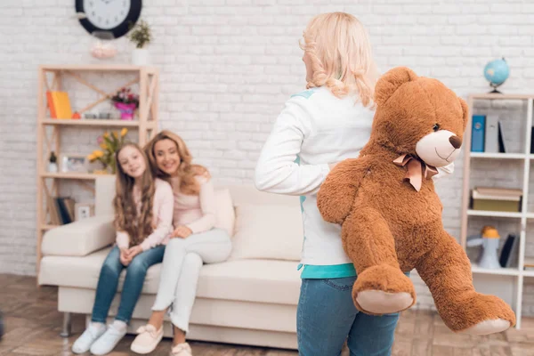 妈妈和奶奶给了一个小女孩一只大玩具熊 他们给她一个惊喜 一家人在家里吃饭 他们有假期 — 图库照片