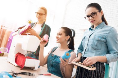 Üç kadın hazır giyim fabrikası'nda. Düğmeler elbisenin tercih ediyor. Onlar mutlu ve moda.