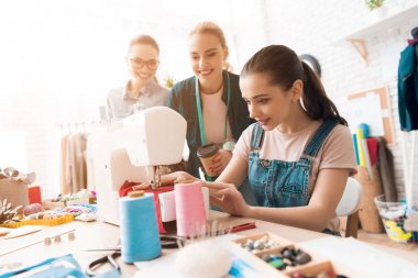 Üç kadın hazır giyim fabrikası'nda. Bunlardan biri yeni elbise dikiş. Onlar mutlu ve moda.