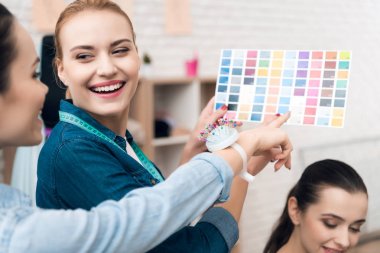 Üç kadın hazır giyim fabrikası'nda. Renk desen için yeni elbise bakıyorlar. Onlar mutlu ve moda.