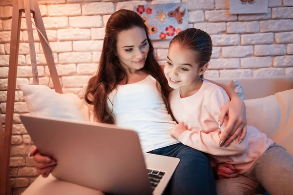 母亲和小女儿看电影在笔记本电脑下灯罩在晚上在家 — 图库照片