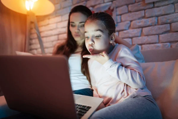 Madre e hija hablando con el padre en el ordenador portátil por la noche en casa . —  Fotos de Stock
