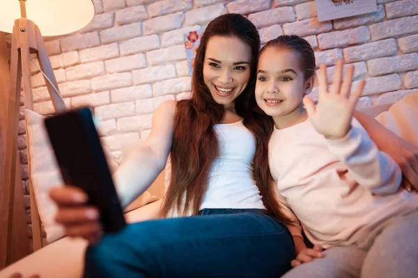 Mother and daughter speaking with father on phone at night at home. — Stock Photo, Image