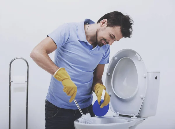 Улыбающийся человек чистит туалет — стоковое фото