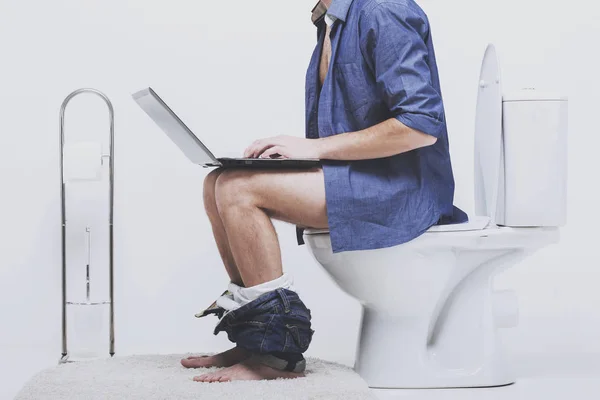 Biznesmen pracuje z laptopa siedząc na sedesie — Zdjęcie stockowe