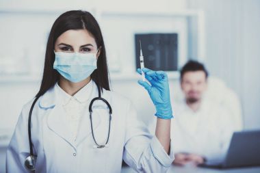 Bir şırınga ile Yardımcısı doktor. Doktor oturur masada arka planı