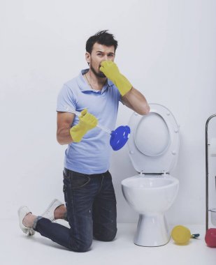 Young man unclogging a stinky toilet with plunger clipart