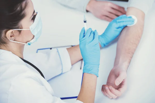 Doctor is making vaccination to the young man in medical room — Stock Photo, Image