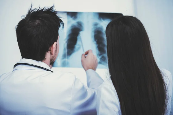 两位年轻的医生正在医院里看 x 光片。后退视图 — 图库照片