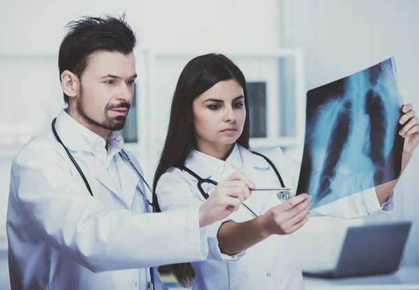 Dos médicos jóvenes están mirando rayos X en el consultorio médico — Foto de Stock