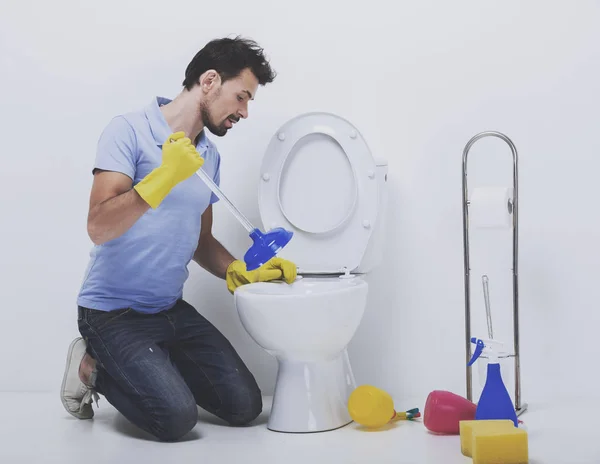 Jeune homme débouchant une toilette avec un piston — Photo