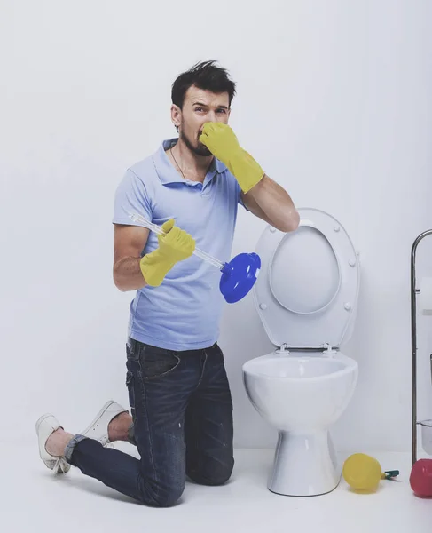 Young man unclogging a stinky toilet with plunger — Stock Photo, Image