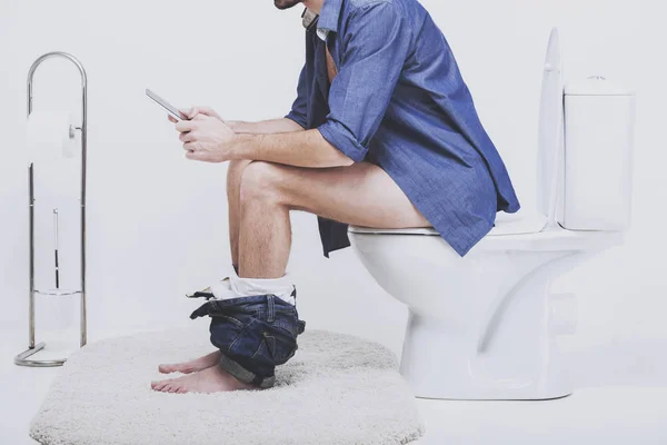 Empresário está trabalhando com tablet digital enquanto sentado no banheiro — Fotografia de Stock
