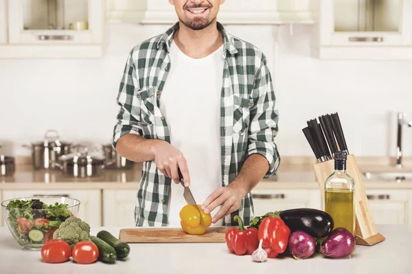 Homem está cozinhando salada de legumes na cozinha — Fotografia de Stock