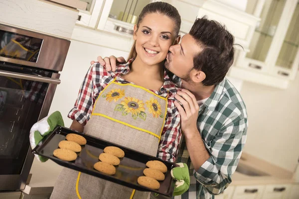 Mooie vrouw houdt hete braadslee met cookies. Gelukkig man is haar kussen — Stockfoto