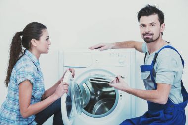 Tamirci ev kadını için bir çamaşır makinesi onarıyor. Beyaz arka plan