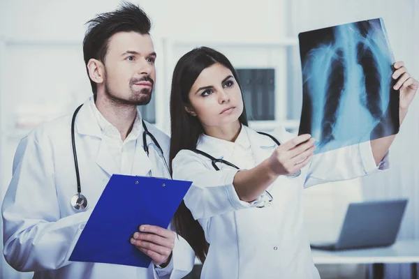 Dwóch młodych lekarzy są patrząc na RTG w gabinecie lekarskim — Zdjęcie stockowe