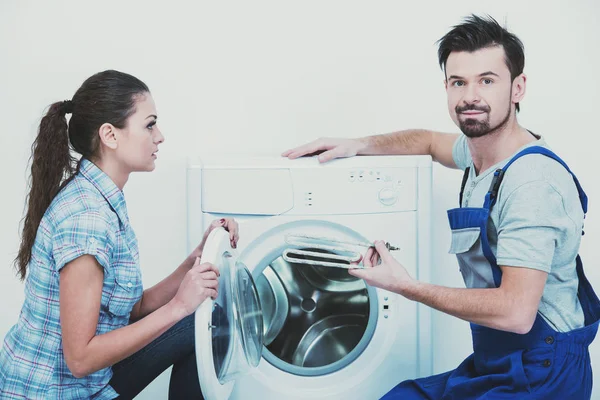 Repairman is repairing a washing machine for housewife. White background — Stock Photo, Image