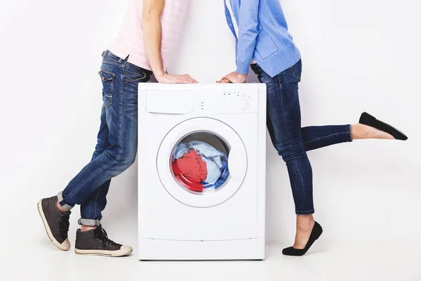 Jovem casal bonito com uma máquina de lavar roupa, no fundo branco — Fotografia de Stock