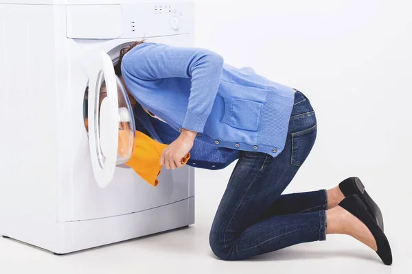 Young woman is searching clothes in washing machine drum — Stock Photo, Image