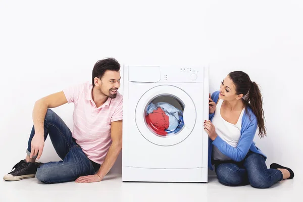 Молодая улыбающаяся пара со стиральной машиной, на белом фоне — стоковое фото