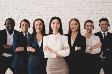 Bir grup genç insan kulaklık-mikrofon ile beyaz bir duvara poz.