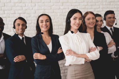 Bir grup genç insan kulaklık-mikrofon ile beyaz bir duvara poz.