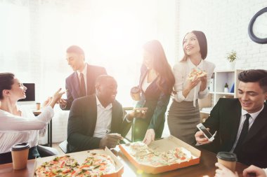 Ofis personeli pizza yemek ve kahve içmek iş ofiste.