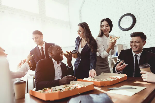 A equipe do escritório come pizza e bebe café no escritório de negócios . — Fotografia de Stock