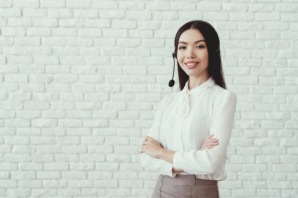 Asiatisk tjej poserar mot vit vägg med headset-mikrofon. — Stockfoto