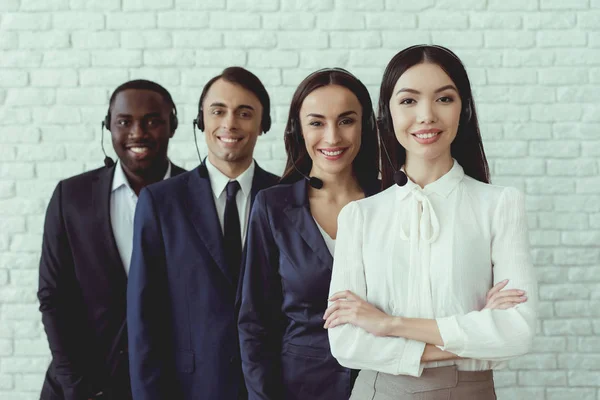 En grupp ungdomar som poserar mot en vit vägg med hörlurar-mikrofoner. — Stockfoto